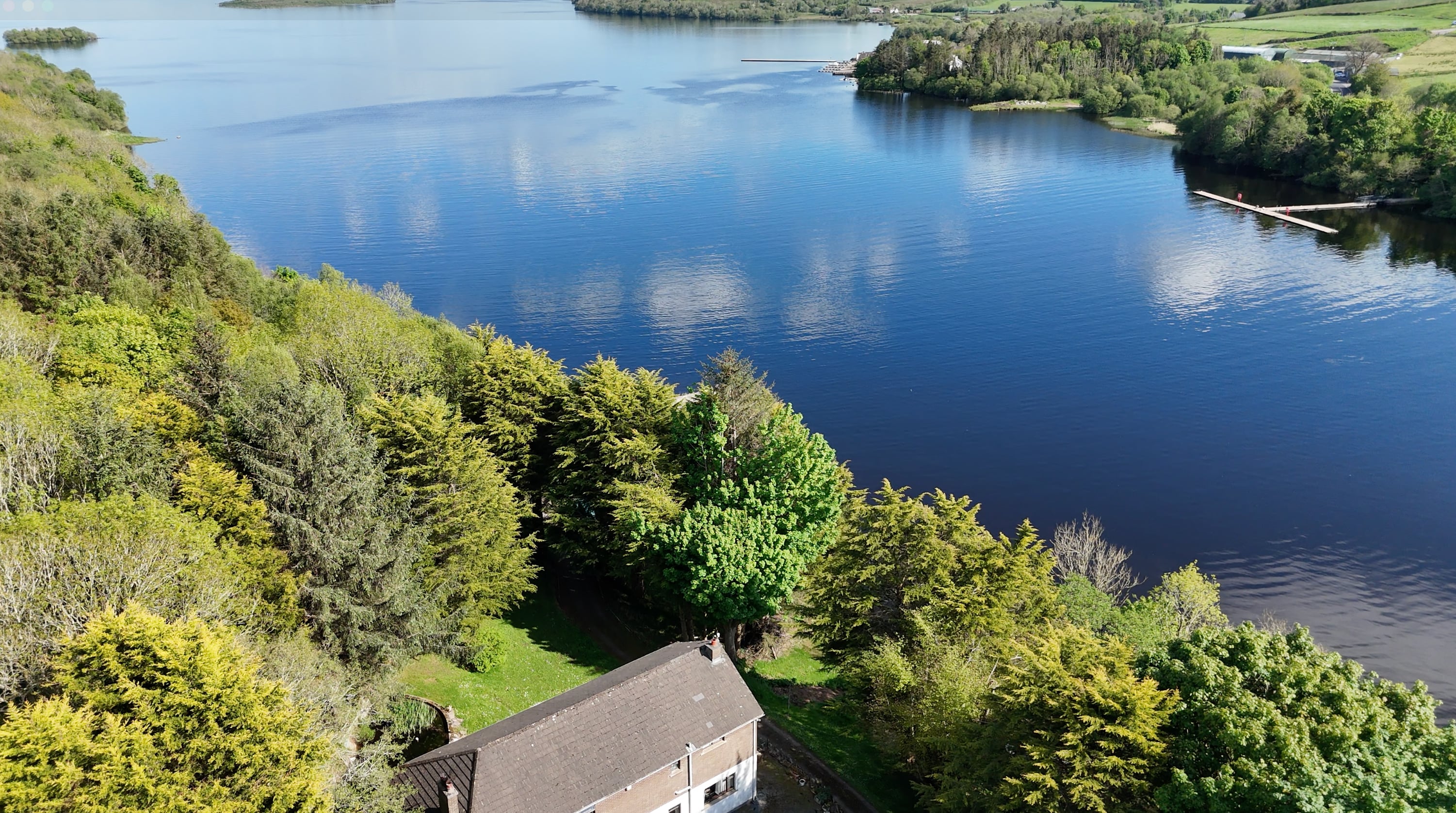 Aerial view across mature trees and the residence towards Lower Lough Erne