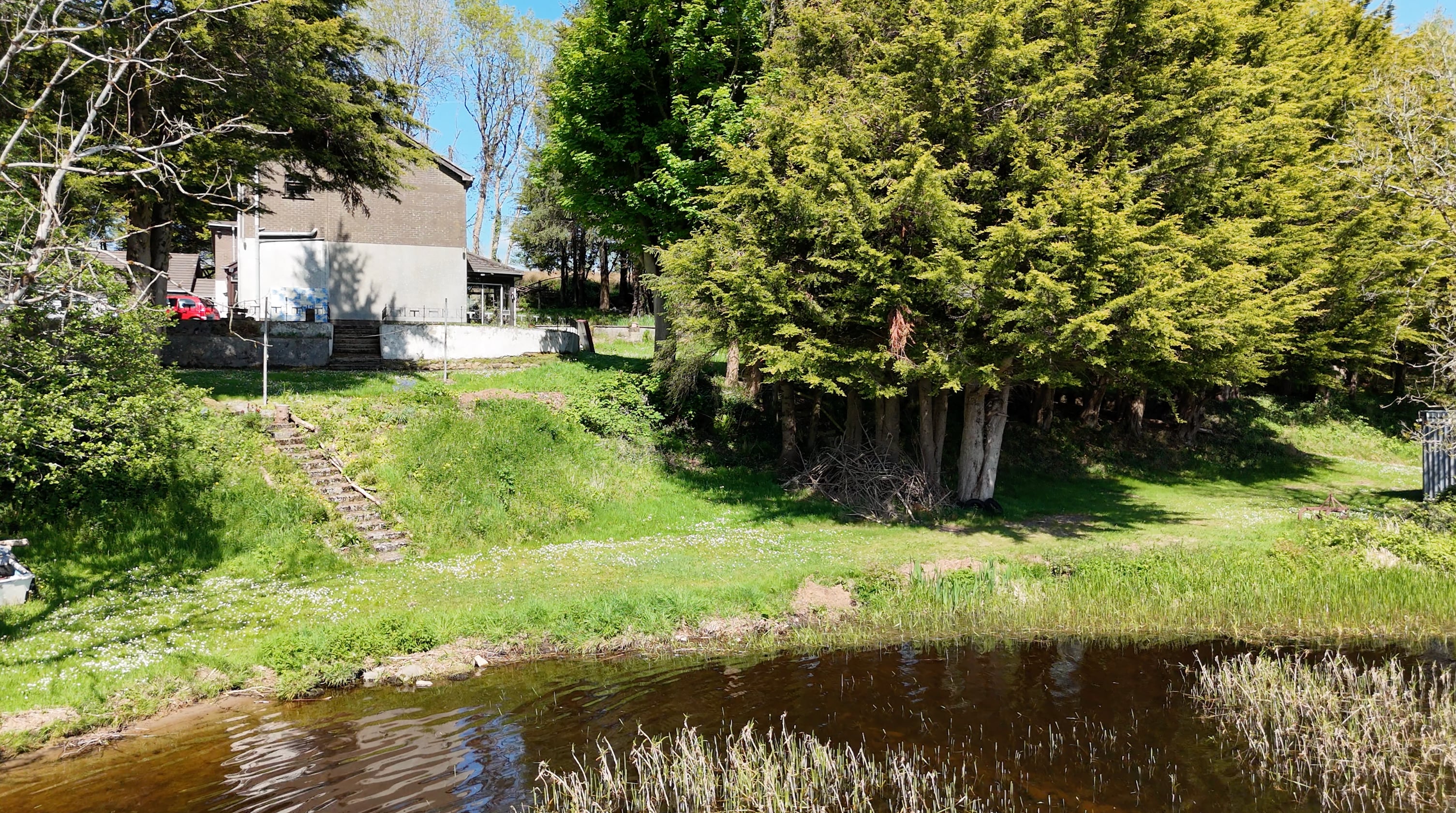 Existing residence and mature trees viewed across the lakeside grounds